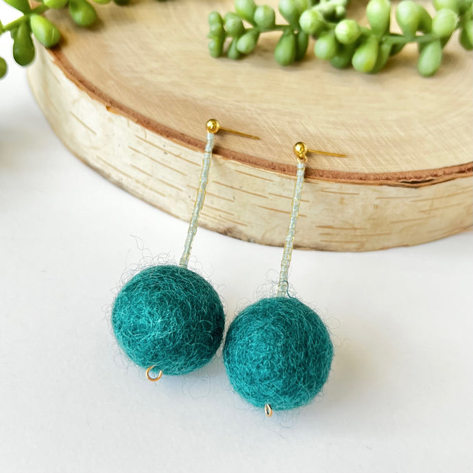 Teal pom pom drop earrings with gold post. Lightweight statement earrings that add a pop of color.